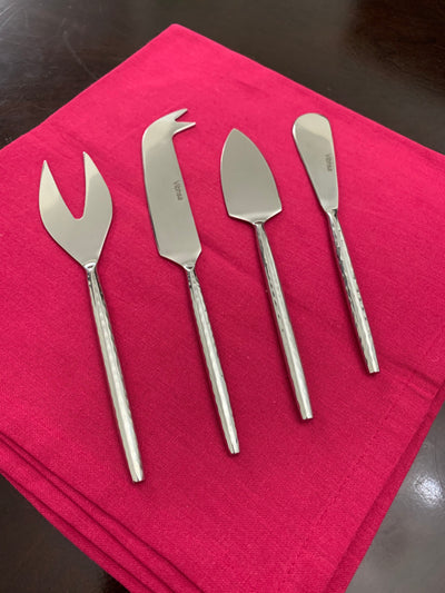 Set of four silver hand-forged cheese knives with hammered handles displayed on a wooden surface