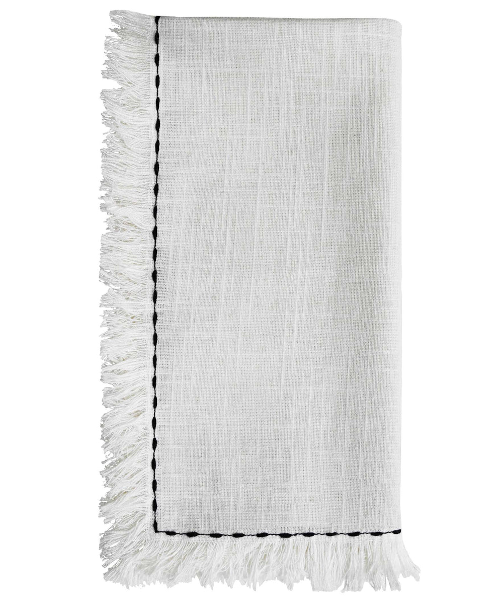 Set of four white cotton napkins with black embroidery placed on a wooden table as dining decor