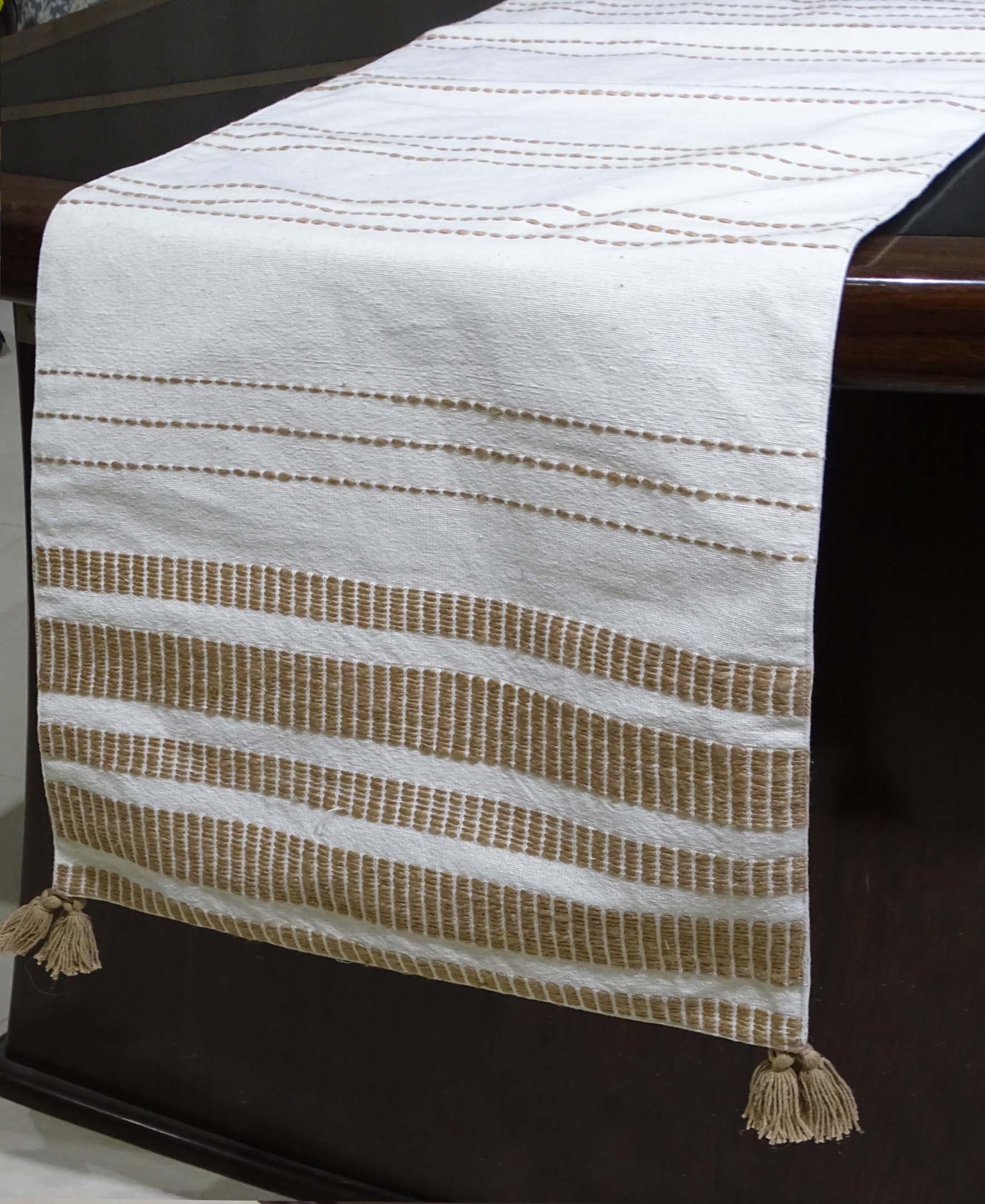 Woven cotton table runner in off white and beige laid on a wooden table