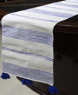 Cotton table runner laid across a dining table with subtle yellow and white stripes