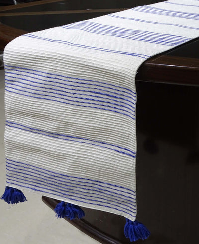 Cotton table runner laid across a dining table with subtle yellow and white stripes