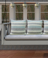 Two decorative pillows with handwoven textured stripes in soft blues, greens, and grays placed side by side on a white cushioned porch swing.