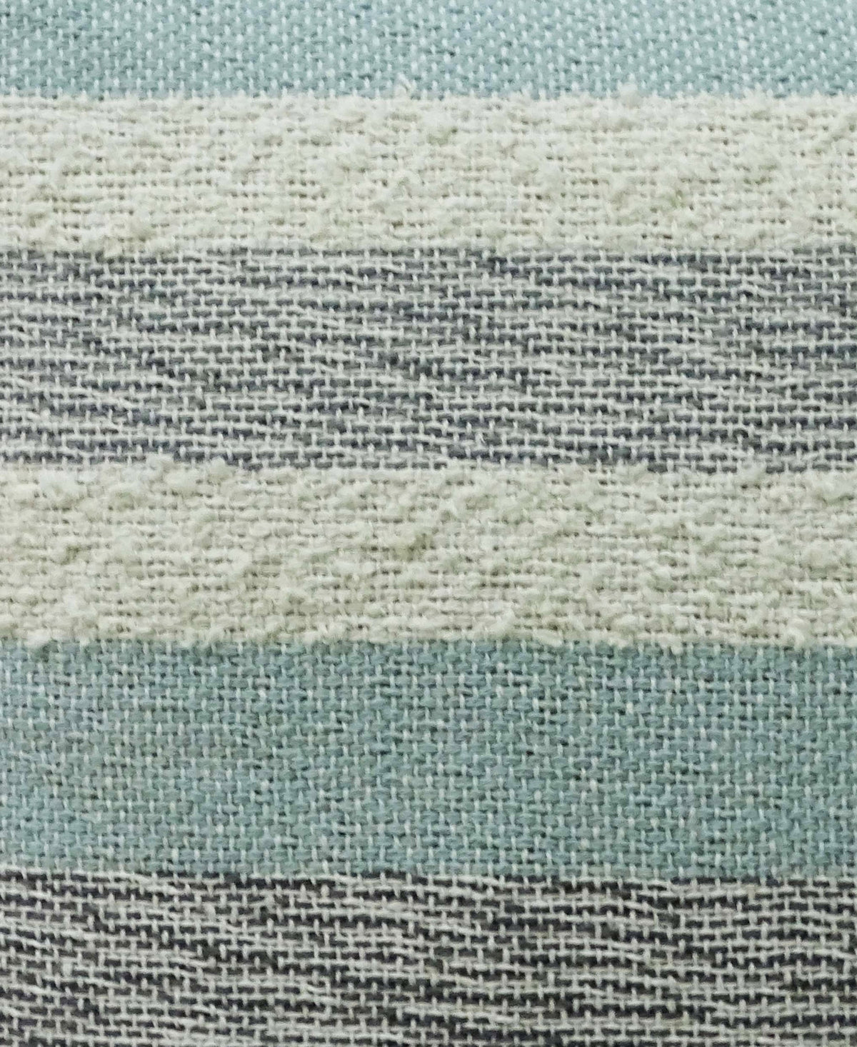 Close-up of textured woven fabric featuring alternating horizontal stripes in muted blue, creamy white, and gray tones with visible fiber detail.