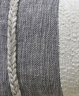 Close-up of a woven throw pillow featuring a central dark gray textured fabric panel bordered by a thick cream-colored braided trim and a cream woven stripe.