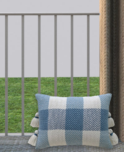 Handloom woven textured plaid decorative pillow with tassels on a woven chair seat