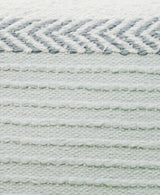 Close-up of a handloom woven pillow showing white and light gray horizontal stripes with textured, raised thread patterns and a zigzag chevron detail at the top