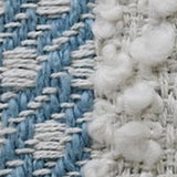 Close-up of a handwoven pillow fabric showing blue and white cotton threads interlaced with fluffy white buttknot edging detail