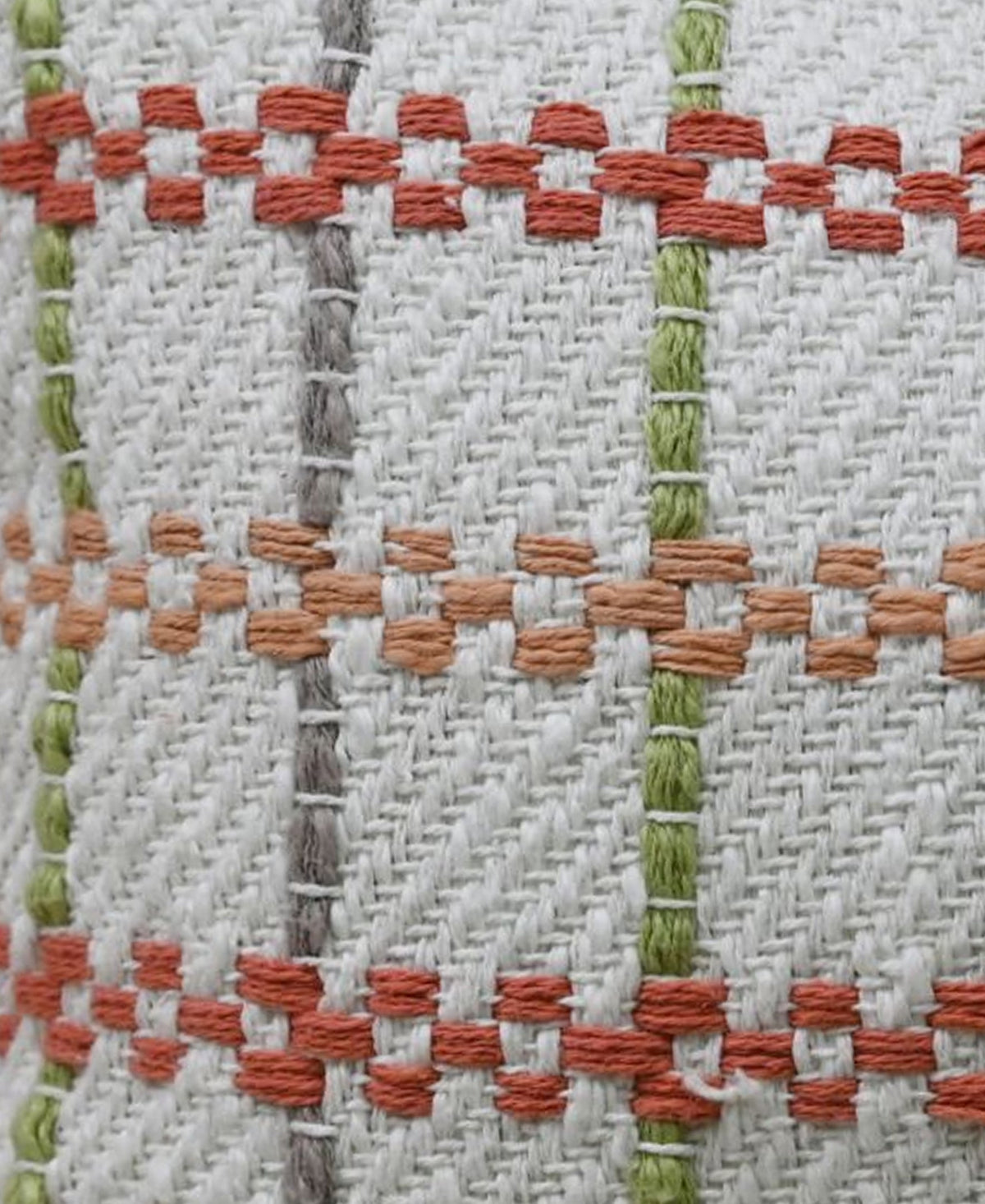Close-up of woven fabric with a grid pattern of vertical green and gray lines intersecting horizontal orange and rust-colored knotted stripes on a beige background.