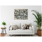 Abstract horizontal canvas with layered rectangular shapes in black, white, and beige tones, framed in wood, hanging above a white sofa with patterned pillows.