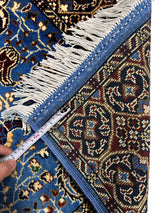 Close-up of a hand-knotted Afghan Parak rug with sky blue floral patterns, beige fringe, and a visible woven back showing intricate geometric motifs, measured by a tape.