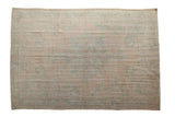 Lightly distressed vintage Oushak carpet in pale beige with subtle hints of blue and green in soft, faded ornate patterns and a simple border design.
