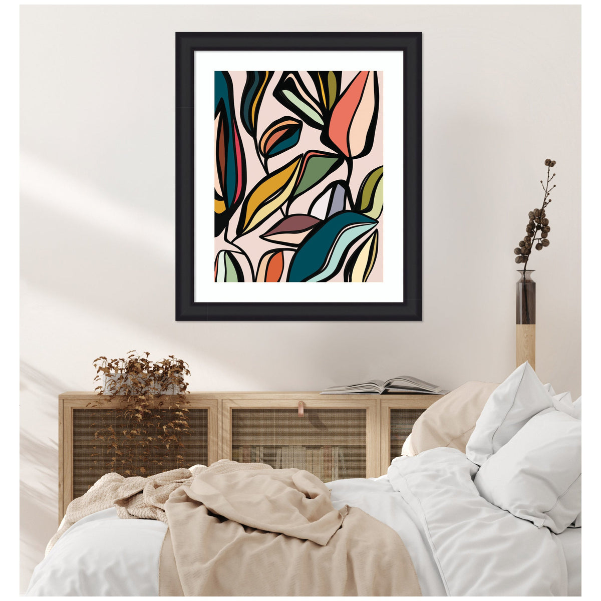 Framed abstract wall art with colorful overlapping leaves in blue, pink, yellow, and green tones above a wooden cabinet and white bed with beige blanket.