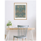 William Morris Peacock and Dragon 1878 framed canvas with intricate teal-blue and gold medieval-inspired pattern hanging above a minimalist wooden desk with a small plant and wire sculpture, paired with a gray spindle-back chair.