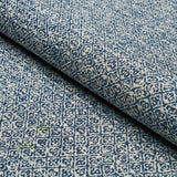 Close-up of indigo blue and white fabric with a tight sarong weave pattern featuring small geometric diamond and floral motifs.