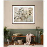 Framed abstract wall art of olive tree branches with muted green and beige leaves against a soft beige and gray background, hung above a wooden bench with cushions and plants.