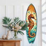 Surfboard-shaped wall art featuring an orange seahorse amid blue swirling waves and coral, mounted vertically on a white paneled wall beside a wooden table with plants.