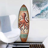 Vertical wooden surfboard wall art featuring a detailed red octopus with swirling tentacles and tribal-style green and white decorative bands at top and bottom.