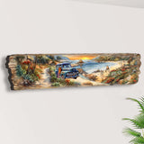 Hand-painted wooden wall art showing a coastal sunset with an old blue pickup truck on a dirt path by the beach, surrounded by trees and rocks.