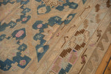 Close-up of a vintage Soumac carpet with intricate geometric patterns in beige, blue, pink, and brown tones, featuring star motifs and zigzag borders.