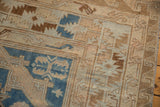 Close-up of a vintage Soumac carpet showing distressed beige and brown geometric patterns with blue accents on a textured fabric base.