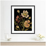 Framed floral artwork featuring large, soft pink and peach flowers with green leaves on a black background, hanging above a white shelf with a glass of water and small bouquet.
