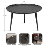 Round black metal coffee table with a scooped, deckled edge tabletop and three tapered legs, featuring a sand-cast textured finish.