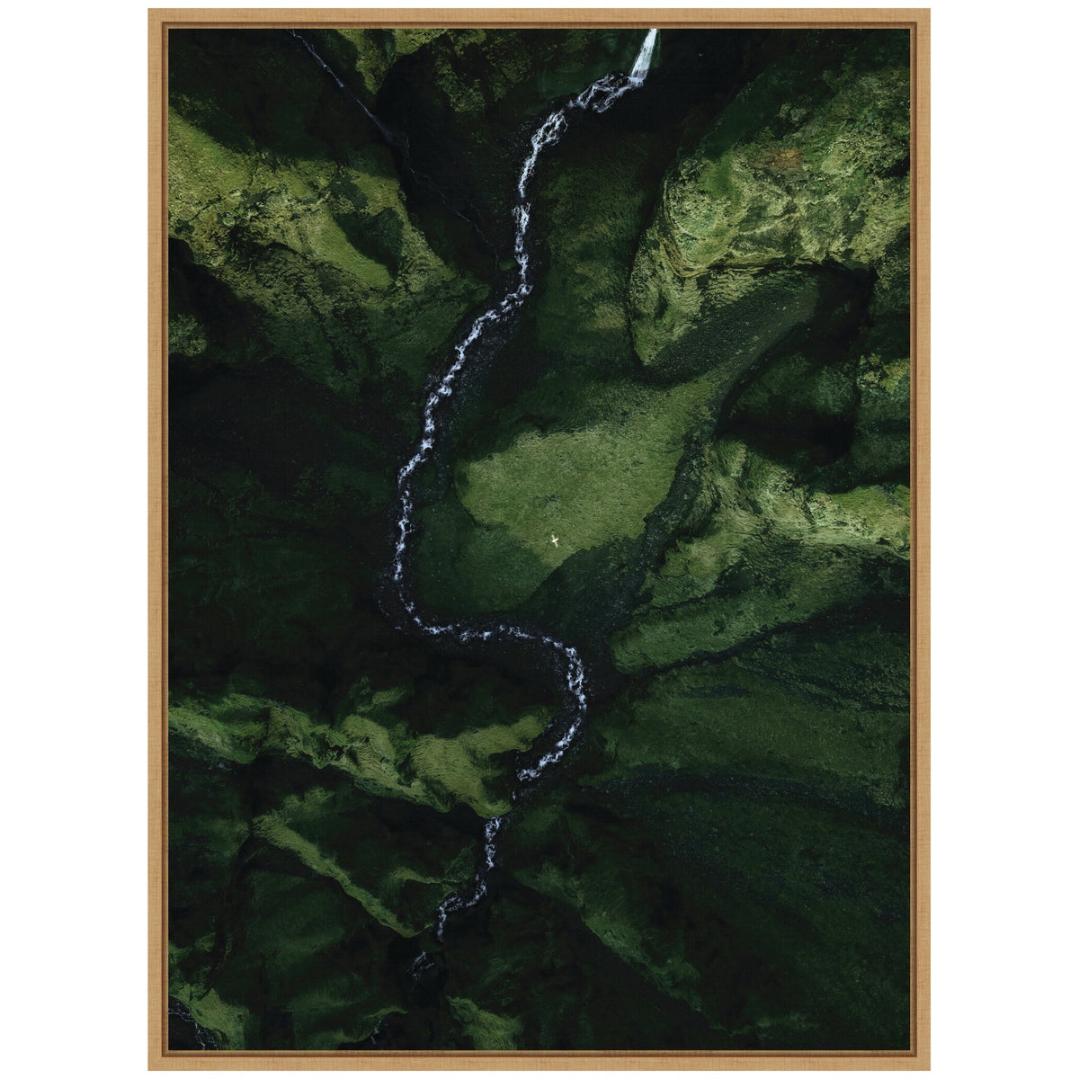 Aerial view of a winding white river cutting through a densely moss-covered green valley with steep cliffs and rugged terrain.