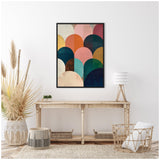 Abstract geometric canvas with overlapping semi-circles in jewel tones of navy, teal, pink, orange, and gold, framed in black and hung above a rustic wooden console.