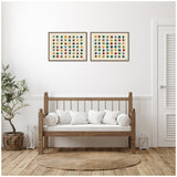 Two framed canvases with rows of multicolored dots in blue, green, orange, and brown, hung above a wooden bench with white cushions in a minimalist room.