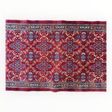 Rectangular vintage Mashhad wool runner with intricate floral patterns in red, blue, and cream, bordered by detailed geometric bands with colorful accents.