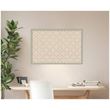 Rectangular pinboard with a green lattice pattern on a beige background, framed in muted green, hanging above a light wood desk with white chair and potted plant nearby.