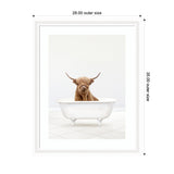 Framed print of a brown Highland cow with long hair and large horns standing inside a white clawfoot bathtub against a plain white tiled background.