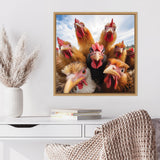 Framed photo of seven curious chickens with red combs and wattles peering closely at the camera against a bright blue sky, displayed above a white desk with books and a woven chair.