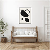 Minimalist living room with wooden bench, white cushions, round jute rug, and framed black abstract shapes on white canvas centered above bench.