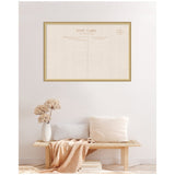 Framed vintage-style linen fabric pinboard designed like a postcard with beige background, hung above a light wood bench with neutral pillows and a vase with dried flowers.