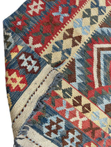 Close-up of colorful Afghani Maimana Kilim runner rug corner showing geometric patterns in red, blue, beige, and brown with fringed edge and interlocking motif bands.