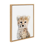 Portrait of a cheetah cub with soft fur and expressive dark eyes against a plain white background in a natural wood frame.