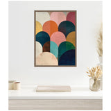Framed abstract canvas featuring overlapping rounded arches in jewel tones including teal, navy, orange, mustard, and pink, displayed on a white wall above a minimal desk with neutral decor.