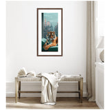 Framed vertical artwork of a tiger lounging on a teal sofa with a New York City skyline background, hanging on a white wall above a wooden bench with a blanket.
