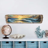 Long wooden plaque painted with a coastal scene showing a golden sunset, crashing blue-green waves, rocky cliffs, and a ship with white sails in the distance.