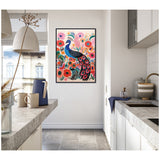 Framed canvas print of a blue and pink peacock amidst bright red and pink flowers on a white wall in a modern kitchen with grey countertops and white cabinets.