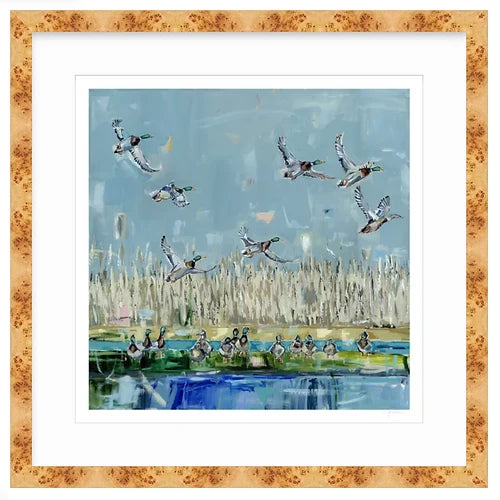 Painting of mallard ducks flying above and resting near a blue-green pond, with beige reeds and a pale blue sky in the background, framed in light wood.