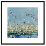 Painted scene of mallard ducks flying and swimming near tall beige reeds and a reflective blue water body under a light blue sky, framed in black and white matting.