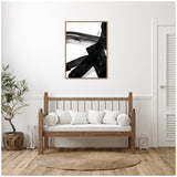 Abstract black brushstroke painting in a wooden frame hangs above a wooden bench with white cushions, flanked by a green potted plant and a lantern in a minimalist room.