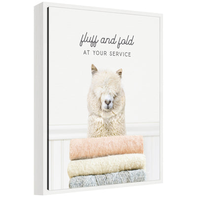 Framed floating canvas art titled 'Sylvie Alpaca Fluff and Fold' depicting an alpaca in laundry scene