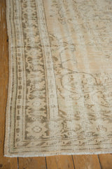 Distressed vintage Oushak carpet in beige and light brown tones with faded geometric and floral patterns on a wooden floor.