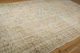 Light beige vintage distressed Oushak carpet with subtle floral and geometric patterns in faded brown and cream tones, laid on wooden flooring.