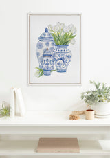 Framed canvas artwork by Patricia Shaw depicting three blue-and-white Chinoiserie jars with white tulips in the largest jar, displayed above a white mantel with decor.