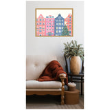 Cozy beige upholstered chair with wooden legs and armrest, orange knitted blanket, and black side table holding a large wood-grain vase with green foliage, below festive framed wall art.