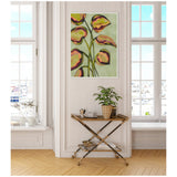 Canvas painting of abstract foliage in shades of green, orange, and pink, hung on a beige wall between two tall windows in a bright room.